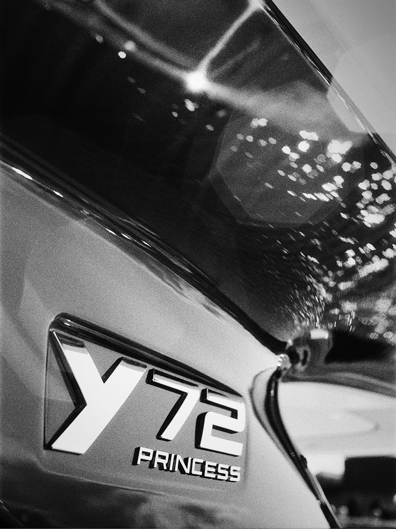Close-up black and white photo of the Princess Y72 model badge on the yacht’s hull, with reflections of light and water.