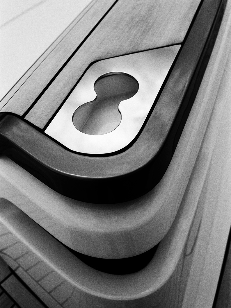 Black and white close-up of a polished metal fitting inset into teak decking, with a figure-eight cut-out.