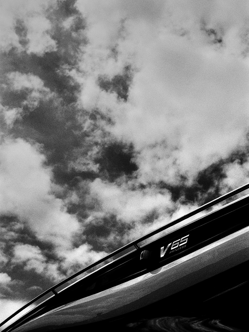 Black and white photo of the upper deck of a Princess V65 yacht against a dramatic cloudy sky.