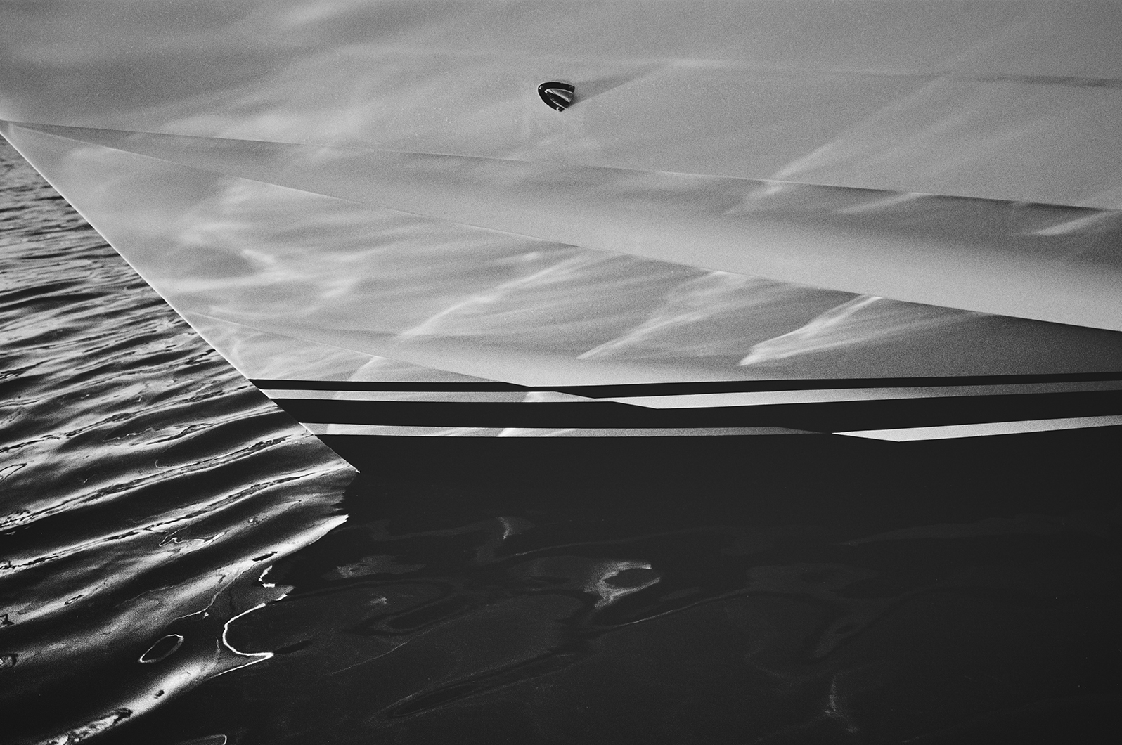 Black and white close-up of a Princess yacht bow, with light reflections on the hull above rippling water.