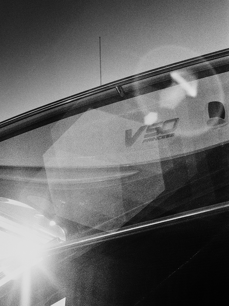 Black and white photo of a Princess V50 yacht, showing the model name through a window with sun glare.